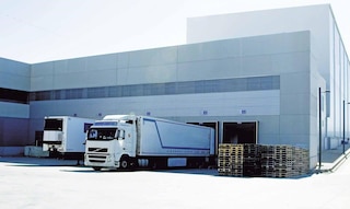 Des camions déchargent leurs marchandises dans un entrepôt, étape intégrante des flux logistiques du cross-docking.